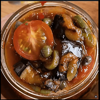A rustic Sicilian caponata eggplant relish cooked down with sweet and sour tomatoes, capers, and olives